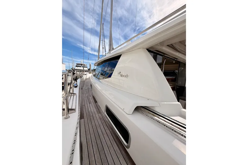 Cross Wind Yacht Photos Pics 2016 Moody Decksaloon 54 yacht with sleek design and wooden deck, docked under blue sky.