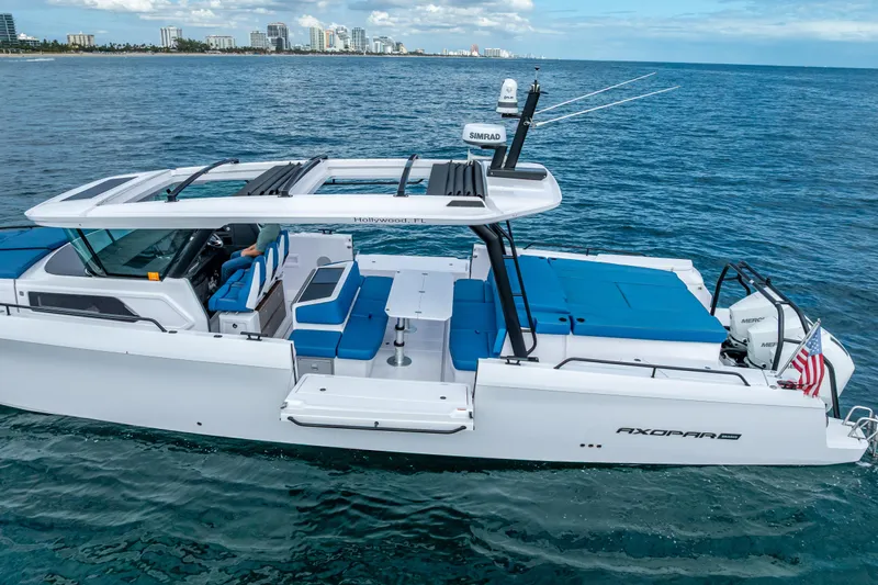  Yacht Photos Pics 2025 Axopar 45 Cross Top boat cruising on open water near city skyline.