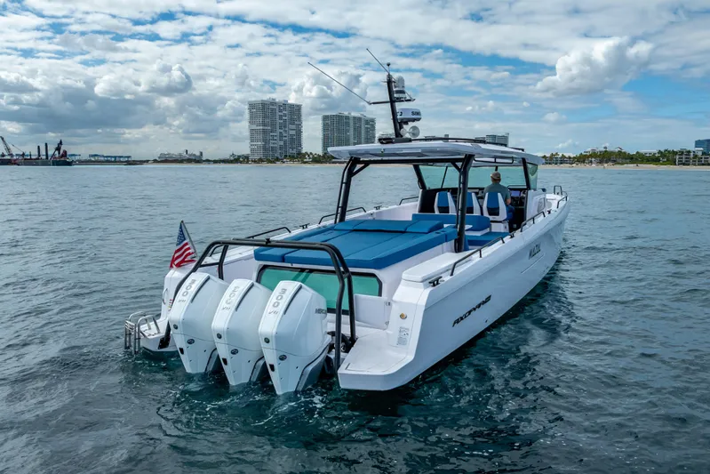  Yacht Photos Pics 2025 Axopar 45 Cross Top boat cruising on open water with city skyline backdrop.