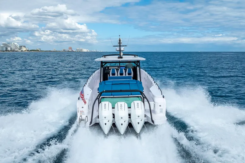  Yacht Photos Pics 2025 Axopar 45 Cross Top boat cruising on open ocean with city skyline in background.