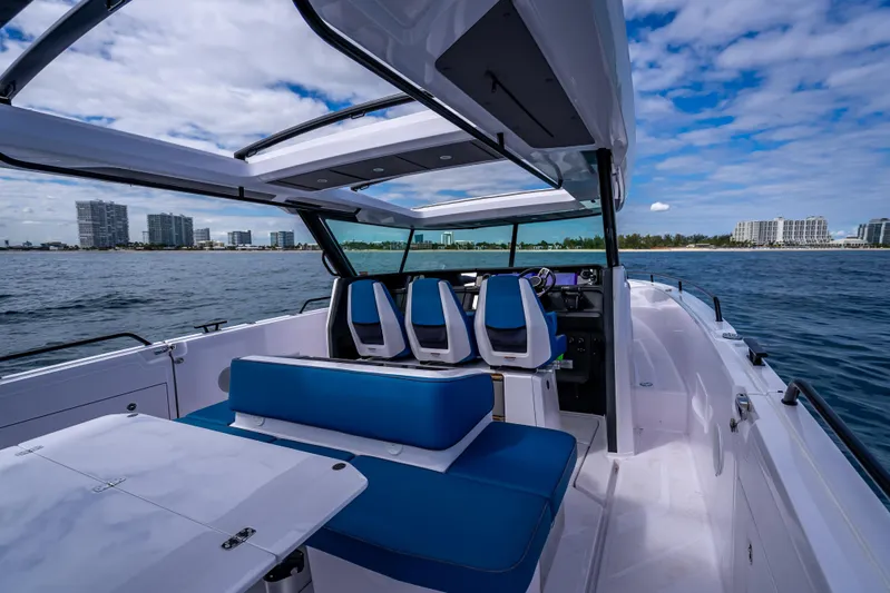 Yacht Photos Pics 2025 Axopar 45 Cross Top boat interior with blue seating, ocean view, and city skyline.