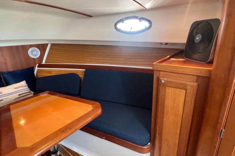 Indigo Yacht Photos Pics 2005 Back Cove 29 interior with wooden table, blue seating, and fan.