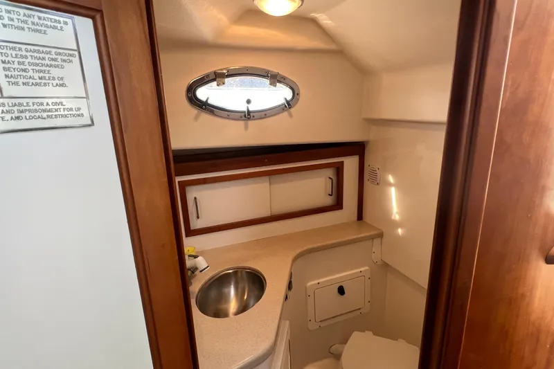 Indigo Yacht Photos Pics 2005 Back Cove 29 boat bathroom with sink, porthole, and storage cabinet.