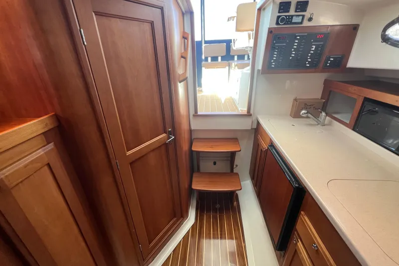 Indigo Yacht Photos Pics 2005 Back Cove 29 interior with wood cabinetry, compact kitchen, and control panel.