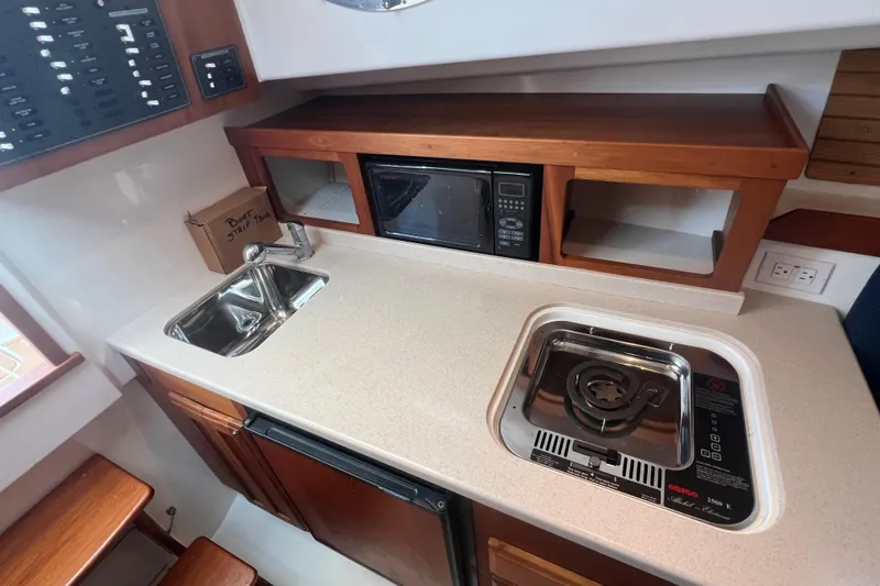 Indigo Yacht Photos Pics 2005 Back Cove 29 boat galley with sink, stove, microwave, and wooden cabinetry.
