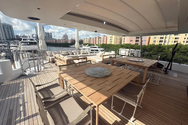 Mr. D Yacht Photos Pics Luxurious 2015 Benetti 140 yacht deck with elegant seating and dining area, docked in a marina.