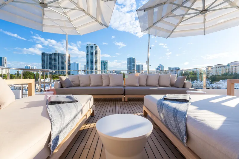 Mr. D Yacht Photos Pics Luxurious Benetti 140 yacht deck with plush seating, city skyline view, and umbrellas, 2015 model.