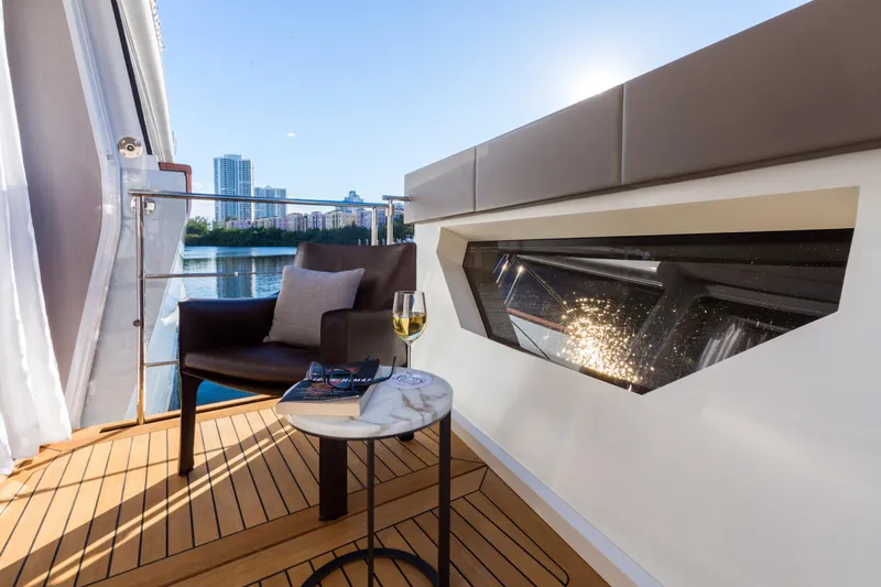 Mr. D Yacht Photos Pics Luxurious Benetti 140 yacht deck with chair, table, wine glass, and cityscape view.