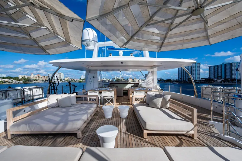 Mr. D Yacht Photos Pics Luxurious 2015 Benetti 140 yacht deck with sun loungers and umbrellas, overlooking a scenic waterfront.