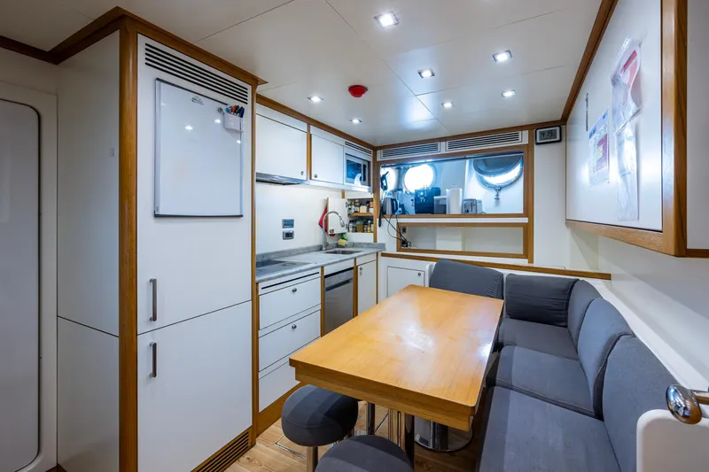 Mr. D Yacht Photos Pics Modern kitchen and dining area on a 2015 Benetti 140 yacht, featuring sleek cabinetry and seating.