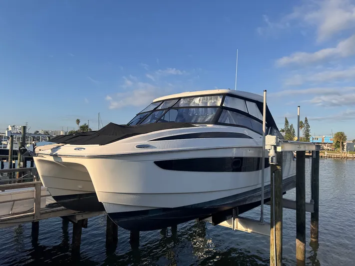  Yacht Photos Pics 2023 Aquila 32 Sport boat docked on a lift under a clear blue sky.