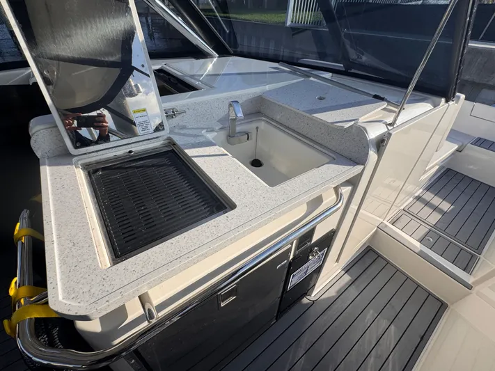  Yacht Photos Pics Outdoor kitchenette on 2023 Aquila 32 Sport boat with sink and grill.