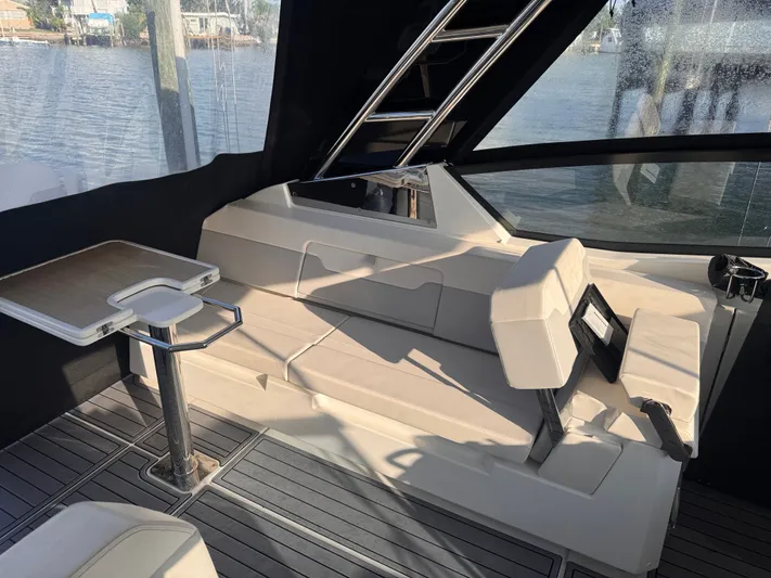  Yacht Photos Pics Interior of 2023 Aquila 32 Sport boat with seating and table, docked by the water.