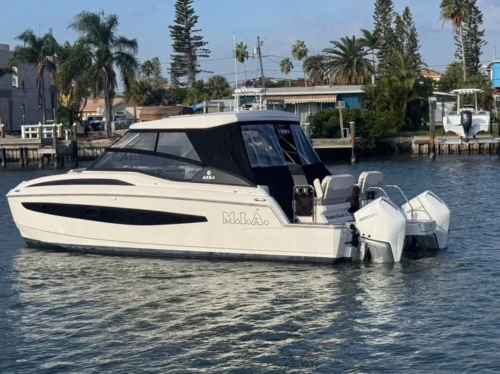  Yacht Photos Pics 2023 Aquila 32 Sport boat on water, surrounded by palm trees and waterfront homes.