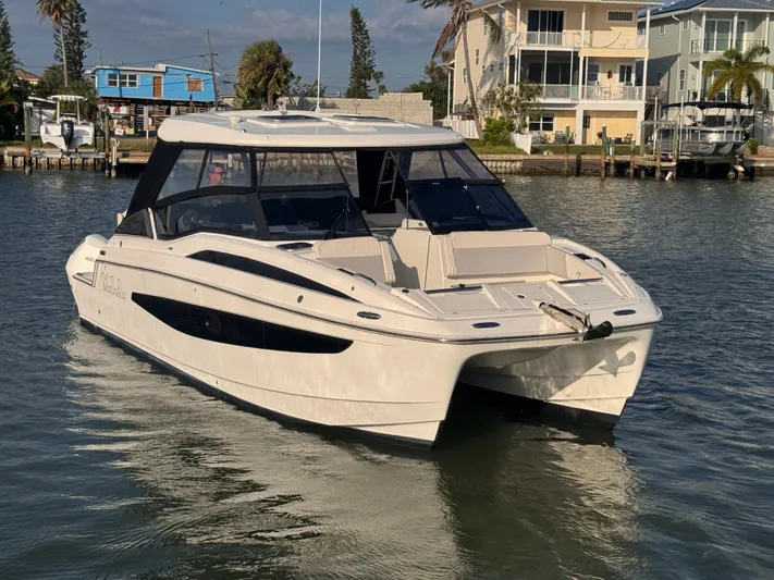  Yacht Photos Pics 2023 Aquila 32 Sport boat on water near waterfront homes.