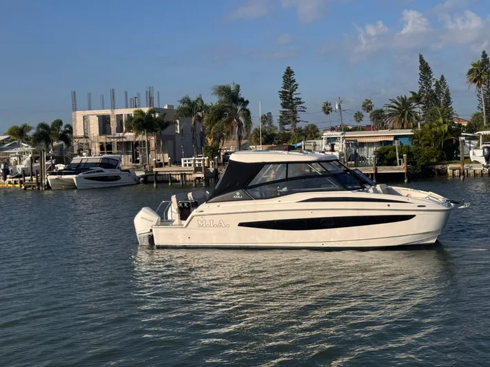  Yacht Photos Pics 2023 Aquila 32 Sport boat on water near palm trees and buildings.