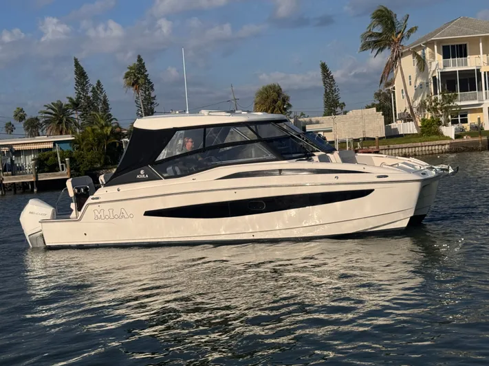  Yacht Photos Pics 2023 Aquila 32 Sport boat cruising on a sunny day near waterfront homes.