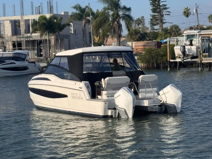  Yacht Photos Pics 2023 Aquila 32 Sport boat with dual Mercury engines on a calm waterway.