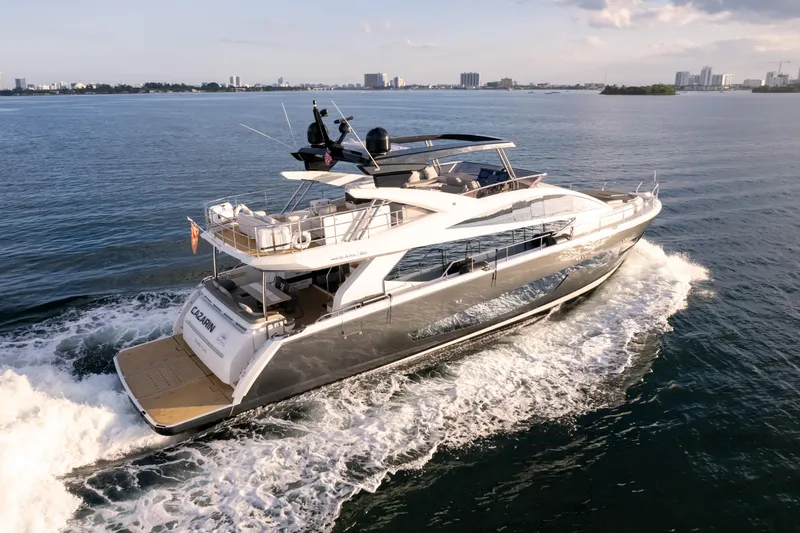  Yacht Photos Pics Luxurious 2020 Pearl 80 yacht cruising on open water with city skyline in background.