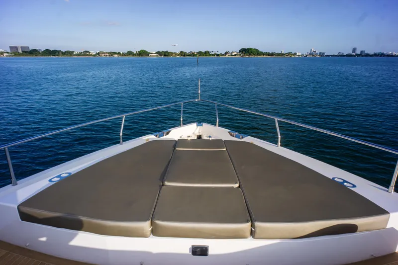  Yacht Photos Pics Bow view of 2020 Pearl 80 yacht with sunbathing area, overlooking calm blue waters.