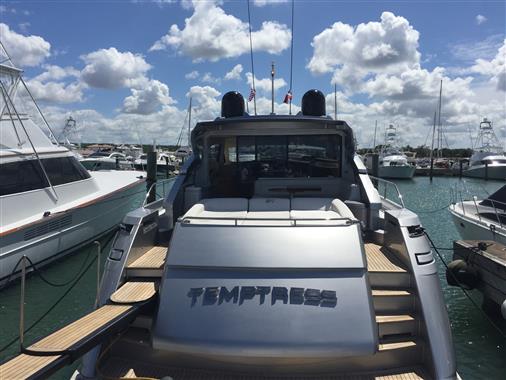 2010 Pershing 64' yacht docked in a marina under a partly cloudy sky.