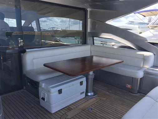 Luxurious seating area on a 2010 Pershing 64' yacht with wooden table and white cushions.