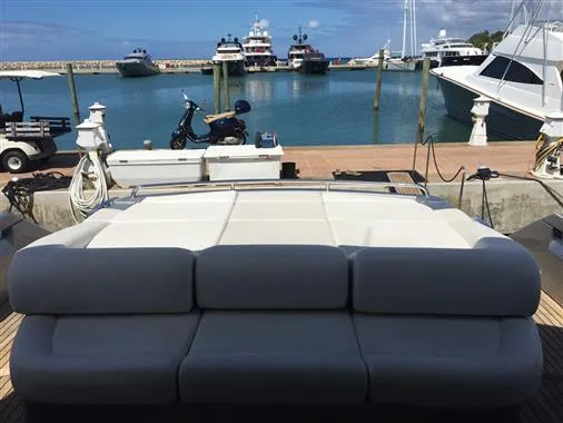 Luxurious 2010 Pershing 64' yacht docked at a marina with scenic ocean view.