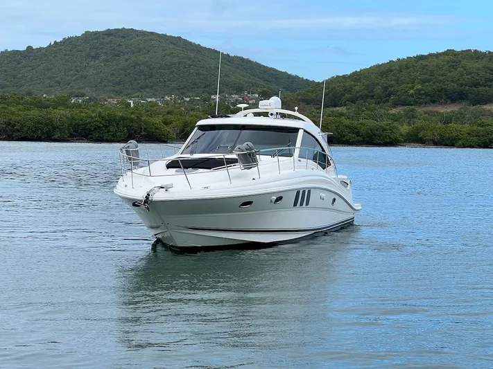  Yacht Photos Pics 2006 Sea Ray 48 Sundancer on calm water with green hills.