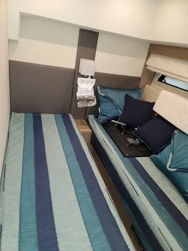  Yacht Photos Pics Interior of a 2016 Prestige 560 yacht with twin beds and blue stripes.