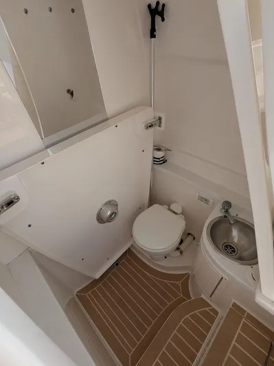  Yacht Photos Pics Compact marine bathroom in 2017 Intrepid 327 Center Console boat, featuring toilet and sink.