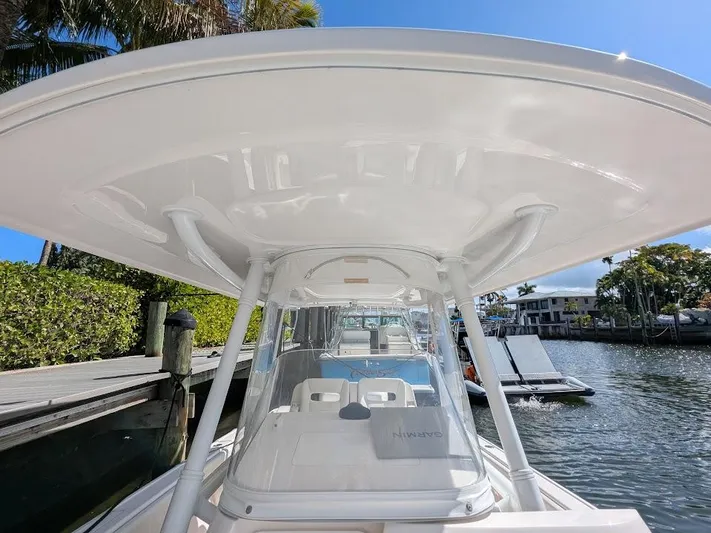  Yacht Photos Pics Intrepid 327 Center Console boat docked, showcasing helm and T-top under clear blue sky.
