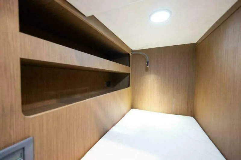 New 2026 Prestige M48 Multihull Yacht Photos Pics Compact cabin interior of 2026 Prestige M48 yacht with wooden shelves and reading light.