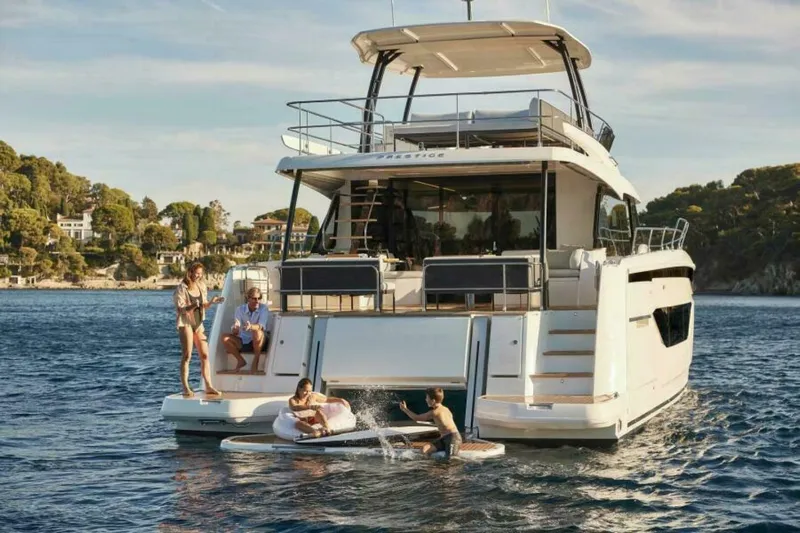 New 2026 Prestige M48 Multihull Yacht Photos Pics 2026 Prestige M48 yacht with people enjoying water activities in a scenic coastal setting.