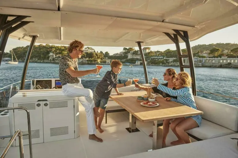 New 2026 Prestige M48 Multihull Yacht Photos Pics Family enjoying a meal on a 2026 Prestige M48 yacht, with scenic ocean views.