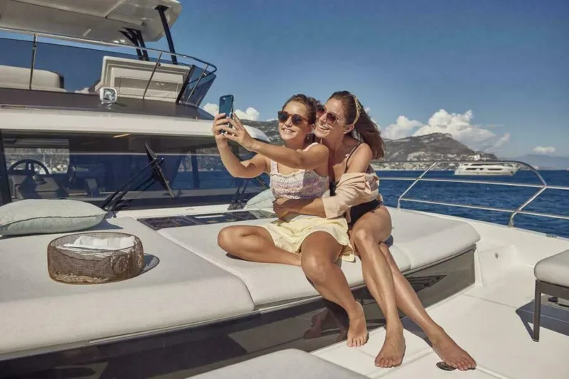 New 2026 Prestige M48 Multihull Yacht Photos Pics Two people taking a selfie on a 2026 Prestige M48 yacht, enjoying sunny weather.
