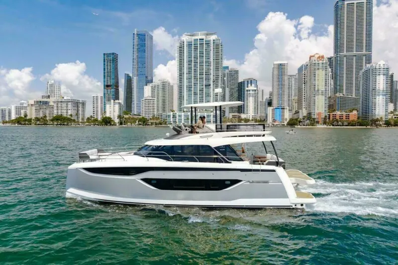 New 2026 Prestige M48 Multihull Yacht Photos Pics Prestige M48 yacht cruising near city skyline, 2026 model, on a sunny day.