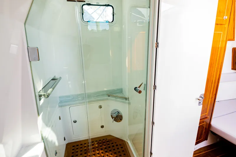  Yacht Photos Pics Luxurious shower area in 2024 HCB 53 Suenos yacht with glass door and wooden accents.