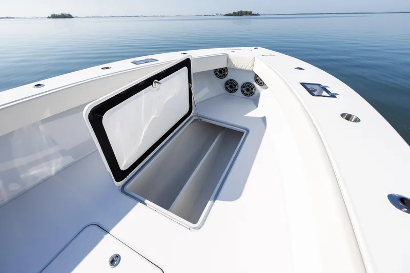 Yacht Photos Pics 2025 Conch 33 boat interior with open storage compartment and speakers on calm water.