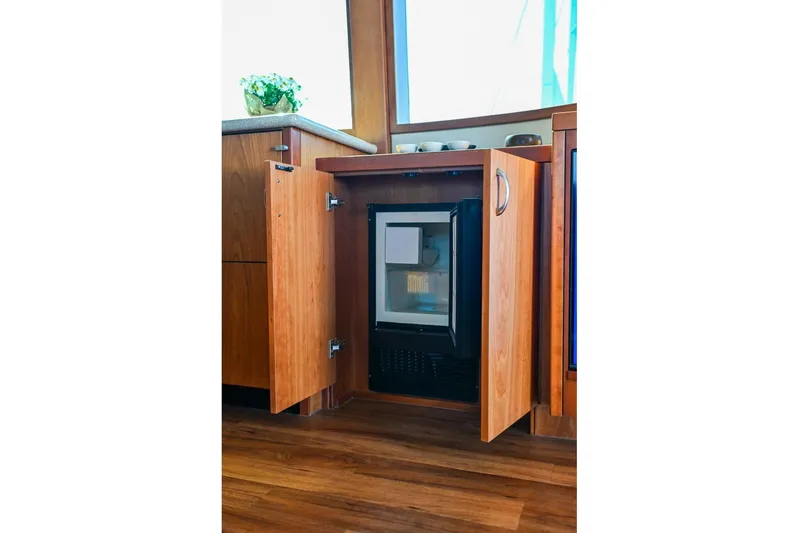 Caraibi Yacht Photos Pics Wooden cabinet with open doors revealing a mini fridge inside a 2013 Hatteras GT63 yacht.
