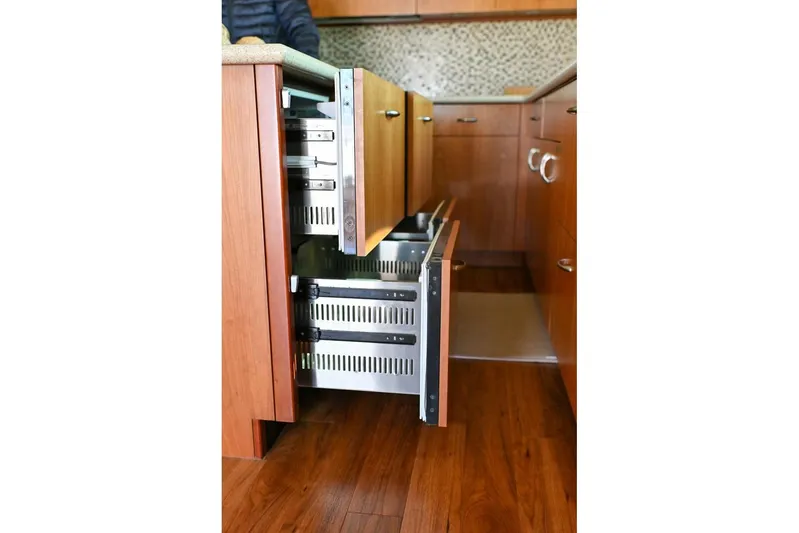 Caraibi Yacht Photos Pics Open wooden cabinet drawers in a 2013 Hatteras GT63 yacht kitchen.