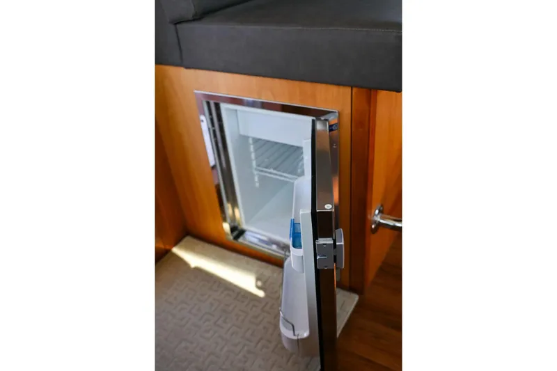 Caraibi Yacht Photos Pics Open mini fridge on 2013 Hatteras GT63 yacht, wooden interior, and carpeted floor.
