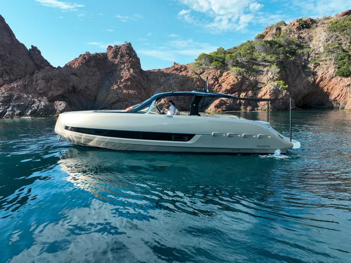  Yacht Photos Pics 2020 Invictus TT460 yacht cruising near rocky coastline under blue sky.