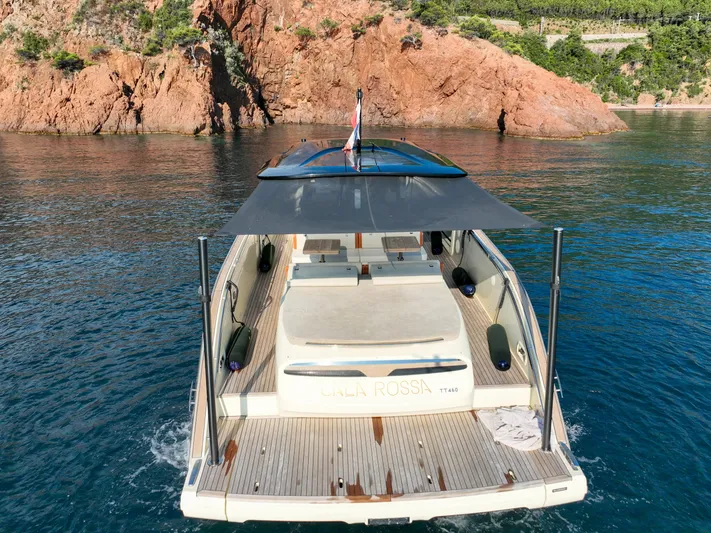  Yacht Photos Pics Invictus TT460 yacht, 2020 model, anchored near rocky coastline with clear blue water.