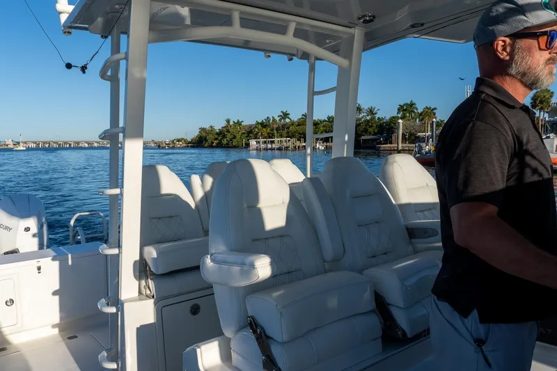  Yacht Photos Pics 2022 World Cat 400 CC-X boat interior with white seating, man steering, scenic water view.