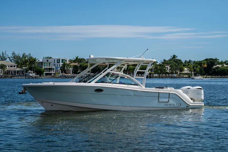  Yacht Photos Pics 2020 Robalo R317 Dual Console boat on calm water, with scenic waterfront background.