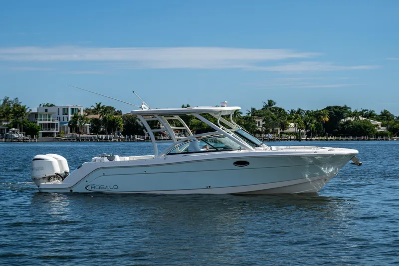  Yacht Photos Pics 2020 Robalo R317 Dual Console boat cruising on a sunny day near waterfront homes.