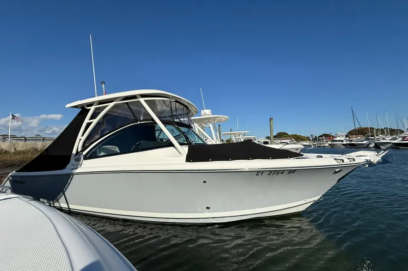  Yacht Photos Pics 2024 Pursuit DC 246 Dual Console boat docked in a marina under clear blue skies.