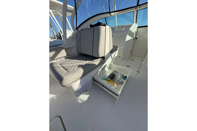  Yacht Photos Pics 2024 Pursuit DC 246 Dual Console interior with cushioned seating and storage drawer open.