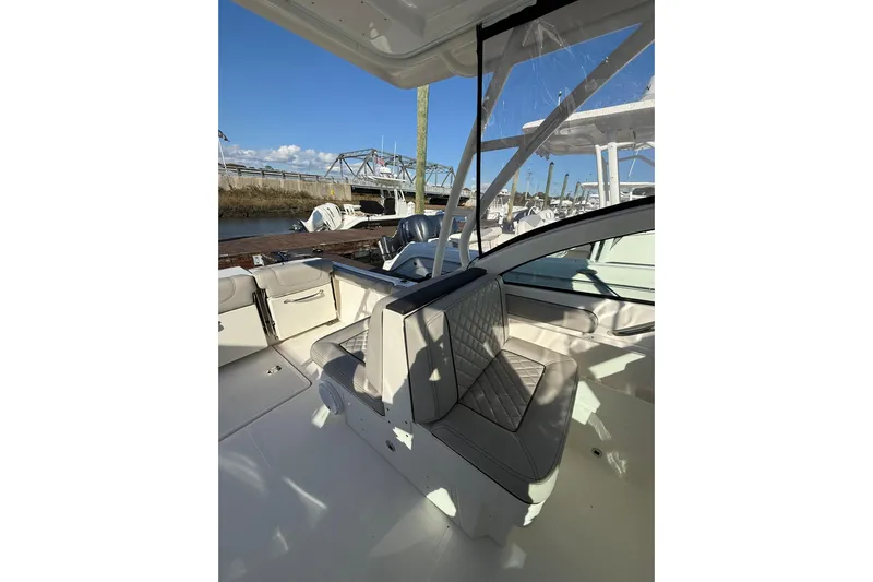  Yacht Photos Pics 2024 Pursuit DC 246 Dual Console boat interior with seating, docked under clear skies.