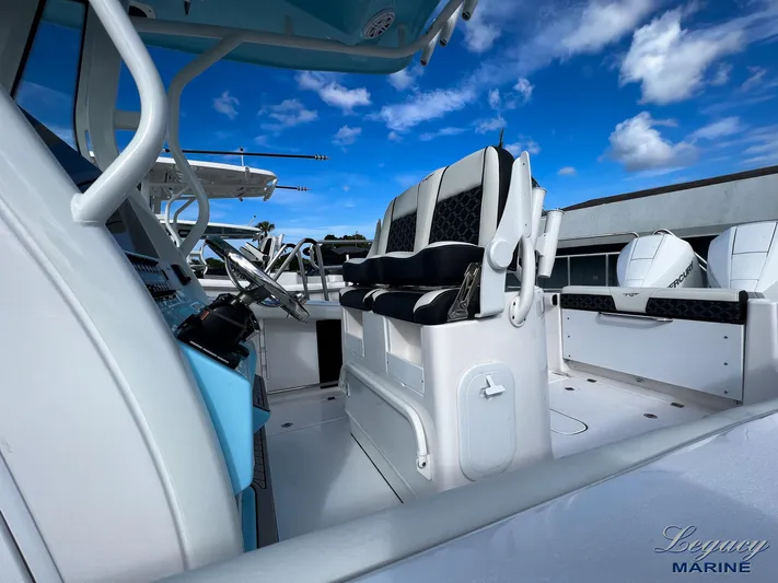  Yacht Photos Pics 2024 Tidewater 272 CC Adventure boat interior with seating and controls under a blue sky.